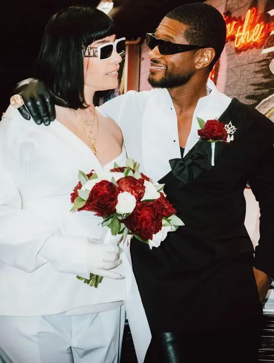 Goicoechea menghindari gaun pengantin biasa, sambil memegang buket bunga peony merah dan mawar putih, ia memilih setelan celana putih yang menampilkan garis leher off-shoulder dan sarung tangan serasi dengan detail kuku berkilauan. [@bellamybrewster]