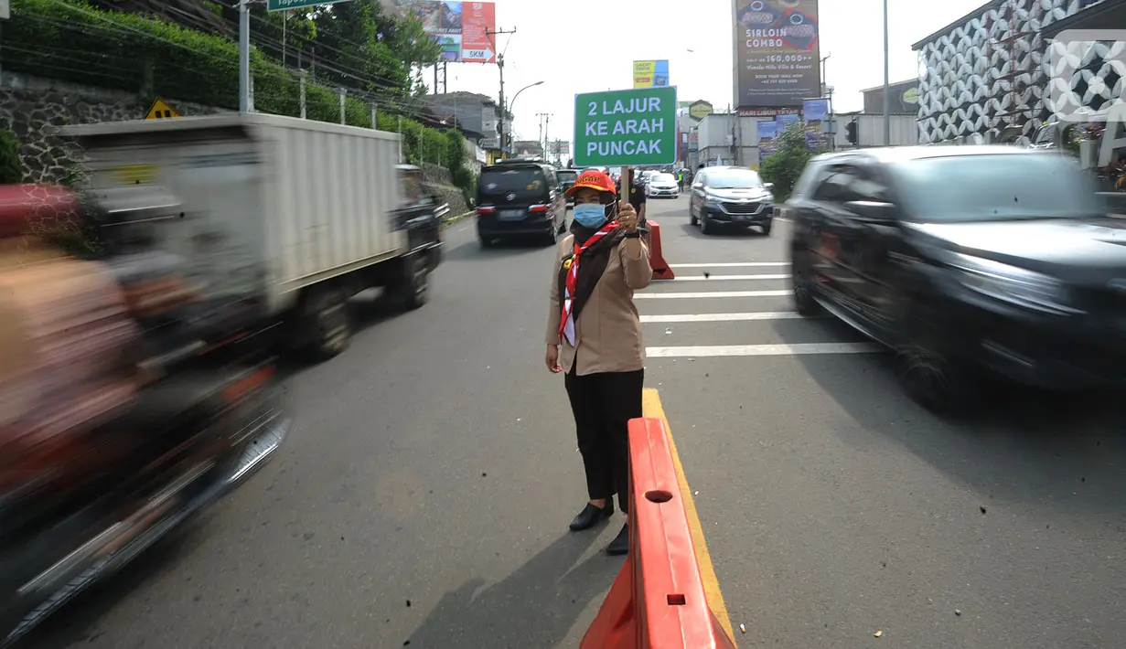 Petugas pramuka membawa papan imbauan saat uji coba sistem kanalisasi 2-1 Jalur Puncak di kawasan Gadog, Bogor, Jawa Barat, Minggu (27/10/2019). Pemberlakuan sistem kanalisasi 2-1 Jalur Puncak sebagai alternatif dari sistem buka-tutup yang telah diberlakukan selama ini. (merdeka.com/Arie Basuki)