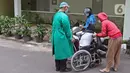Petugas medis (kiri) mendorong pasien yang duduk di kursi roda di IGD RSUD Cengkareng, Jakarta, Rabu (23/6/2021). Meningkatnya kasus COVID-19 di Jakarta membuat pasien harus mengantre di luar IGD untuk mendapatkan tempat perawatan. (Liputan6.com/Herman Zakharia)