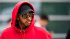Pembalap Mercedes asal Inggris Lewis Hamilton berjalan di paddock sebelum Grand Prix Formula Satu China di Shanghai (12/4). Hamilton keren mengenakan kaca mata dan jaket berwarna merah. (AFP Photo/Johannes Eisele)