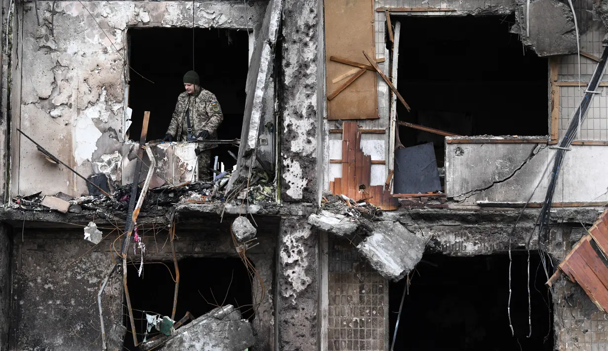 Seorang prajurit Ukraina terlihat di jendela bangunan tempat tinggal yang rusak di Koshytsa Street, pinggiran ibukota Ukraina Kiev (25/2/2022). Presiden Ukraina Volodymyr Zelensky mengatakan pasukan penyerang menargetkan warga sipil dan ledakan terdengar di ibu kota yang terkepung. (AFP/Daniel Leal)