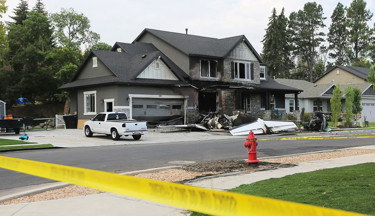 Sebuah pesawat kecil yang sengaja menabrak rumah di Payson, Utah, AS, Senin (13/8). Menurut petugas polisi, dua orang itu bisa melarikan diri meski bagian depan rumah dua lantai tersebut sudah dilalap api. (Scott G Winterton/The Deseret News via AP)