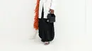 Cynthia Erivo tampil unik dengan kemeja putih dipadu syal bulu oranye-putih di bahu. Rok sequin hitam dan tas kecil hitam jadi pelengkap busana [dok. Dior]