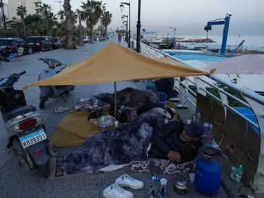 Para pengungsi yang melarikan diri dari serangan udara Israel di Dahiyeh, pinggiran selatan Beirut, beristirahat di tepi pantai Beirut, Lebanon, Jumat 6 Maret 2026. Ratusan orang di Beirut, Lebanon, terpaksa tidur di tepi pantai dan trotoar dengan kondisi seadanya. (AP Photo/Hussein Malla)