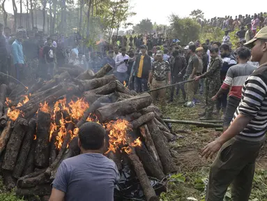Polisi dan pekerja kehutanan bersama penduduk desa menyaksikan tubuh gajah dibakar setelah kereta penumpang melaju menabrak dua gajah yang melintasi rel di desa Batasi dekat perbatasan India-Nepal, sekitar 37 km dari Siliguri (11/12/2019). (AFP/Diptendu Dutta)