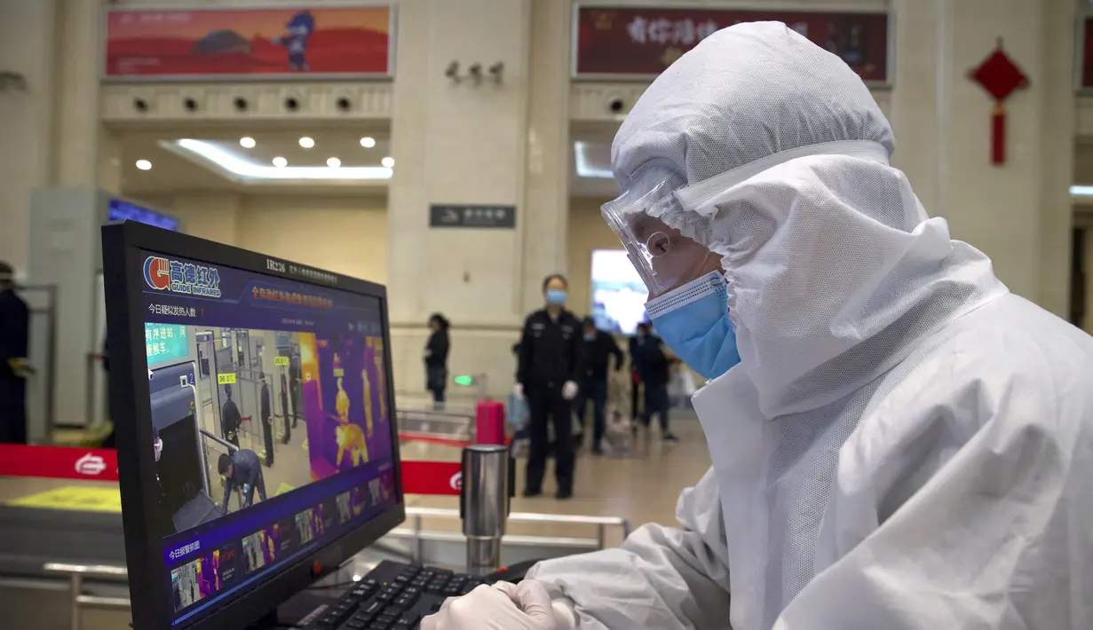 Petugas mengenakan alat pelindung diri saat memonitor pemindai suhu di Stasiun Hankou, Wuhan, Provinsi Hubei, China, Rabu (8/4/2020). Setelah 11 minggu lockdown, layanan kereta di kota yang menjadi titik awal pandemi virus corona COVID-19 ini kembali beroperasi. (AP Photo/Ng Han Guan)
