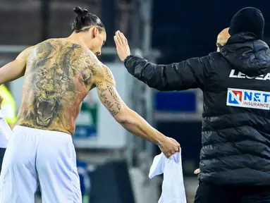 Striker AC Milan, Zlatan Ibrahimovic, menukar jersey saat melawan Cagliari pada laga Liga Italia di Sardegna Arena, Senin (19/1/2021). AC Milan menang dengan skor 2-0. (AFP/Alberto Pizzoli)