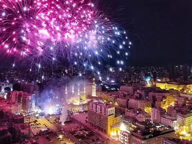 Kembang api menghiasi langit diatas Masjid Mohammad al-Amin saat acara peresmian menyalakan lampu pohon natal di Beirut, Lebanon (10/12). Menyambut datangnya natal, warga Beirut merayakan peresmian pohon natal. (AFP Photo/Stringer)