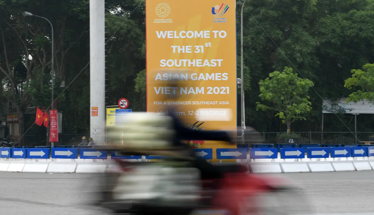 <p>Seorang pengendara melewati rambu untuk Pesta Olahraga Asia Tenggara (Southeast Asian Games) atau biasa disingkat SEA Games ke-31, sehari sebelum upacara pembukaan di Hanoi, Vietnam, Rabu (11/5/2022). SEA Games 2021 akan dibuka pada 12 Mei 2022 di Stadion My Dinh dengan mempertandingkan 40 cabang olahraga (cabor) dalam 526 nomor. (TANG CHHIN Sothy / AFP)</p>