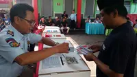 Seorang petugas Lapas Lowokwaru Malang membantu warga binaan memasukkan surat suara usai pencoblosan (Liputan6.com/Zainul Arifin)