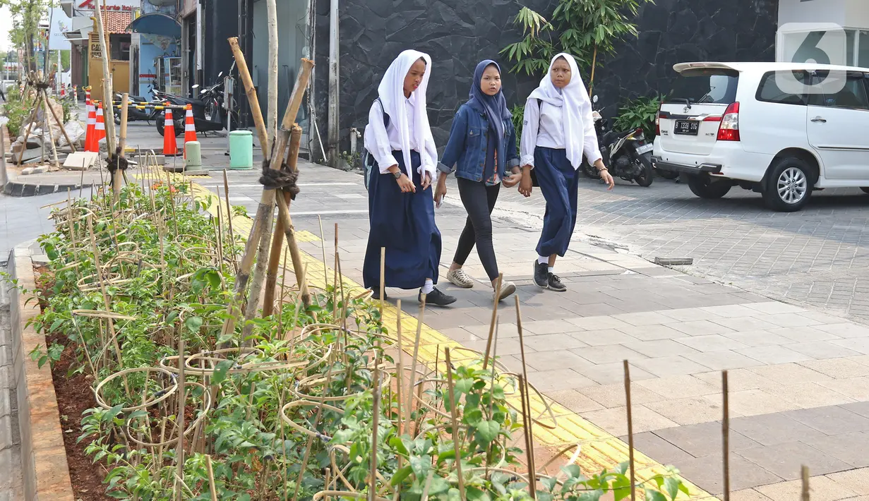 Pelajar melintasi trotoar di kawasan Kemang, Jakarta, Selasa (15/10/2019). Pemerintah Provinsi DKI menargetkan pelebaran dan penataan trotoar ini akan rampung pada Desember 2019. (Liputan6.com/Herman Zakharia)