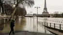 Seorang pria berdiri di tepi sungai Seine di dekat menara Eiffel dan distrik Beaugrenelle, Paris (23/1). Sejumlah kapal di sungai tidak dapat berlayar melewati jembatan kota. (AFP Photo/Ludovic Marin)