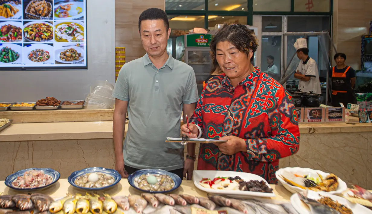 Penduduk desa Li Yafen (kanan) melayani pelanggan di restorannya di Desa Shatangwan, Xiangshan, Kota Ningbo, Provinsi Zhejiang, China, 16 September 2020. Desa nelayan Shatangwan dalam beberapa tahun terakhir mengembangkan pariwisata ekologi yang memanfaatkan lingkungan sekitar. (Xinhua/Jiang Han)