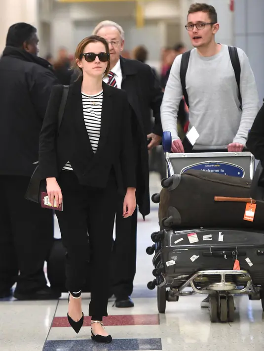 Style Emma Watson sangat cantik dan stylish saat  baru saja tiba di bandara JFK, New York. Emma mengenakan t-shirt stripes alias garis-garis dengan blazer hitam simple yang sangat cantik. (celebmafia.com)