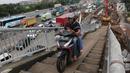 Pengendara motor menaiki Jembatan Penyeberangan Orang (JPO) di kawasan Cikunir, Bekasi Barat, Senin (12/3). Aksi tidak tertib dengan berkendara melintasi JPO itu berpotensi membahayakan pengendara motor maupun pejalan kaki. (Liputan6.com/Arya Manggala)