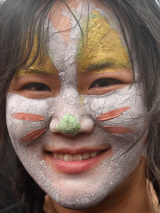 Wajah seorang wanita didekorasi dengan lumpur berwarna selama Boryeong Mud Festival di pantai Daecheon, Korea Selatan, Sabtu (20/7/2019).  Ajang mandi lumpur sepuasnya di Korea Selatan ini, merupakan festival khusus untuk memeriahkan musim panas di negeri ginseng. (Minji SUH/AFP)
