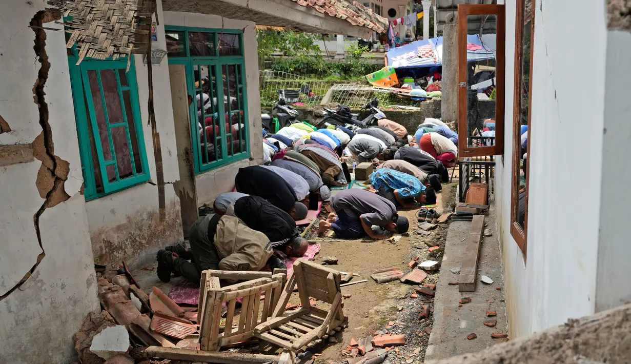 Umat muslim melaksanakan salat Jumat di luar masjid yang rusak parah akibat gempa di Desa Gasol, Cianjur, Jawa Barat, Indonesia, Jumat (25/11/2022). Gempa dengan magnitudo 5,6 yang mengguncang Cianjur pada 21 November 2022 lalu telah menewaskan 272 orang, 2.046 orang luka-luka, dan sebanyak 62.545 orang mengungsi. (AP Photo/Achmad Ibrahim)
