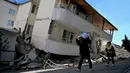Orang-orang berjalan di sebuah jalan melewati sebuah bangunan yang rusak, setelah gempa berkekuatan 7,8 magnitudo yang melanda beberapa wilayah di Turki dan Suriah, Kamis 16 Februari 2023. (OZAN KOSE/AFP)