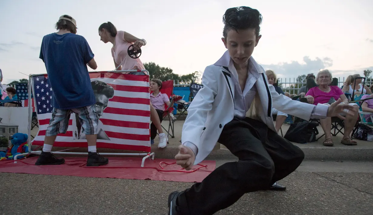 Seorang anak berpakaian menyerupai Elvis Presley pada peringatan 40 tahun kematian sang idola di Graceland, Memphis, Selasa (16/8). Penggemar yang ambil bagian dalam perayaan itu harus membayar Rp 365ribu untuk menyalakan lilin. (AP Photo/Brandon Dill)