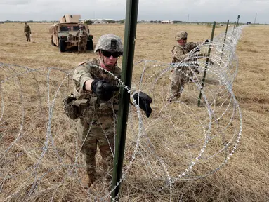 Tentara AS memasang kawat duri dekat jembatan perbatasan antara AS dengan Meksiko di Donna, Texas, Minggu (4/11). Presiden AS Donald Trump mengatakan kehadiran pasukannya untuk mengantisipasi 'invasi' imigran. (AP Photo/Eric Gay)