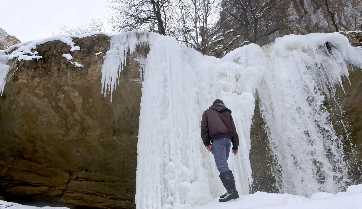 Pengunjung bermain di dekat Air Terjun Mirusha yang membeku, di Lapceve, Kosovo, Senin (9/1). Ekstremnya cuaca yang melanda sebagian eropa menyebabkan puluhan orang tewas dan keberangkatan pesawat di tunda. (AFP Photo/Armend Nimani)