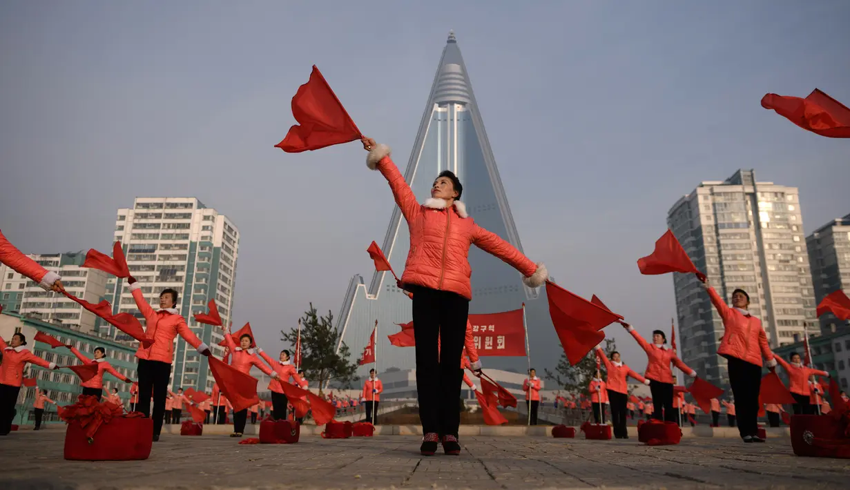 Kelompok Serikat Wanita Sosialis mengibarkan bendera saat melakukan propaganda di depan Hotel Ryugyong, Pyongyang, Korea Utara, Sabtu (9/3). Mereka mengibar-ngibarkan bendera sambil menyanyikan lagu-lagu patriotik selama jam sibuk. (Ed Jones/AFP)
