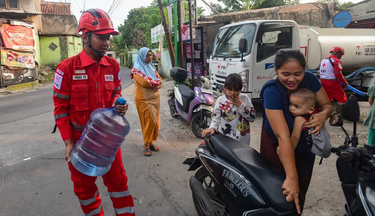 Petugas Palang Merah Indonesia (PMI)  membantu warga membawa air galon di RW 08. Cipayung Jaya, Kota Depok, Jawa Barat, Jumat (14/07/2026).