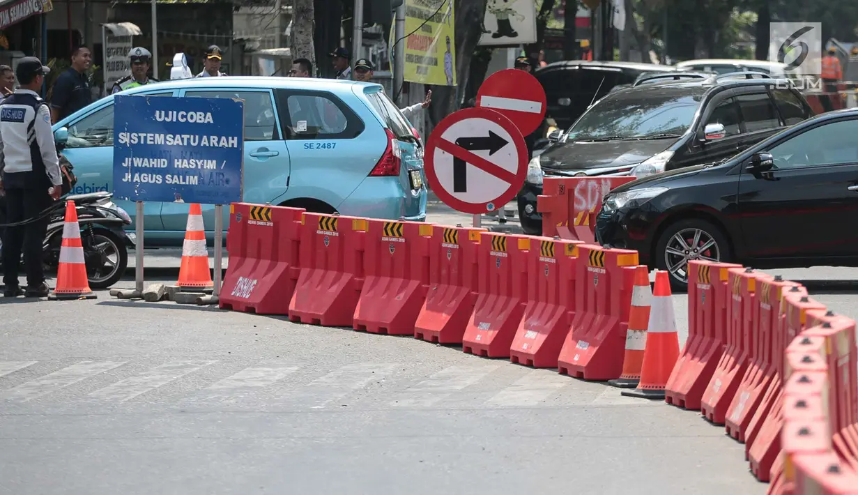 Petugas mengatur lalu lintas saat uji coba sistem satu arah di Jalan KH Wahid Hasyim, Jakarta, Selasa (9/10). Dalam uji coba tersebut, kendaraan dari arah Jalan Agus Salim dilarang berbelok menuju Jalan KH Wahid Hasyim. (Liputan6.com/Faizal Fanani)