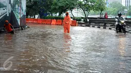 Petugas PPSU Kel Kuningan Barat mencari saluran pembuangan air di putaran kolong fly over Kapt Tendean, Jakarta, Selasa (9/2/2016). Hujan yang mengguyur Jakarta sore ini mengakibatkan putaran ini tergenang air. (Liputan6.com/Helmi Fithriansyah)