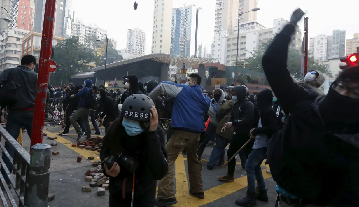 Pengunjuk rasa melemparkan batu ke arah wartawan yang meliput aksi protes yang berujung bentrok di Mongkok, Hong Kong, Selasa (9/2). Bentrokan dimulai ketika pemerintah daerah mencoba untuk menertibkan PKL yang beroperasi. (REUTERS / Bobby Yip)