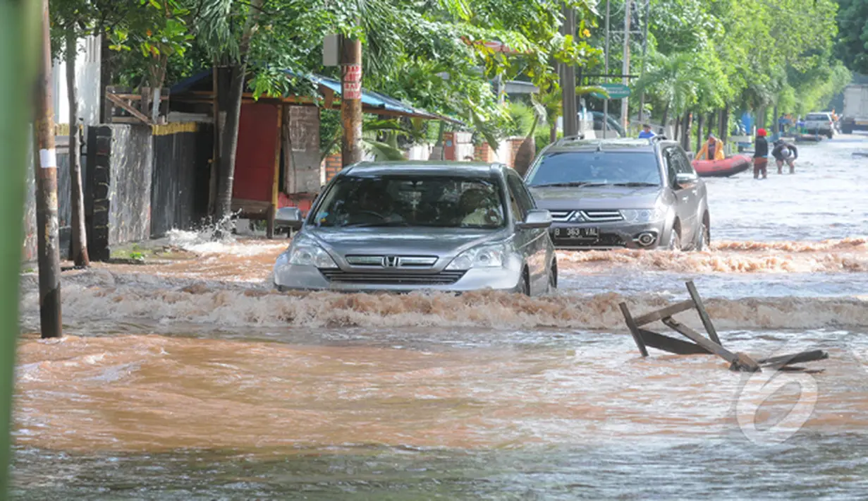 Hujan yang mengguyur Jakarta sejak Minggu (8/2) lalu, membuat Waduk Ria Rio meluap. Tampak 2 buah kendaraan menerobos banjir di kawasan Perumahan Pulomas, Jakarta, Selasa (10/2/2015). (Liputan6.com/Herman Zakharia)