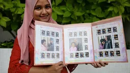 Pekerja pos Nurshafiqa Kasim berpose dengan prangko bergambar PM Malaysia Mahathir Mohamad di sebuah kantor pos di Kuala Lumpur, Selasa (10/7). Prangko bergambar Mahathir ini dijual dalam edisi terbatas. (Mohd RASFAN/AFP)