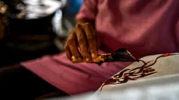 Seorang pekerja membuat desain batik di sebuah bengkel di Banda Aceh, Aceh, Rabu (13/10/2021). Pemilihan warna membuat kain batik Aceh terlihat cerah dan juga glamor. (Chaideer MAHYUDDIN/AFP)