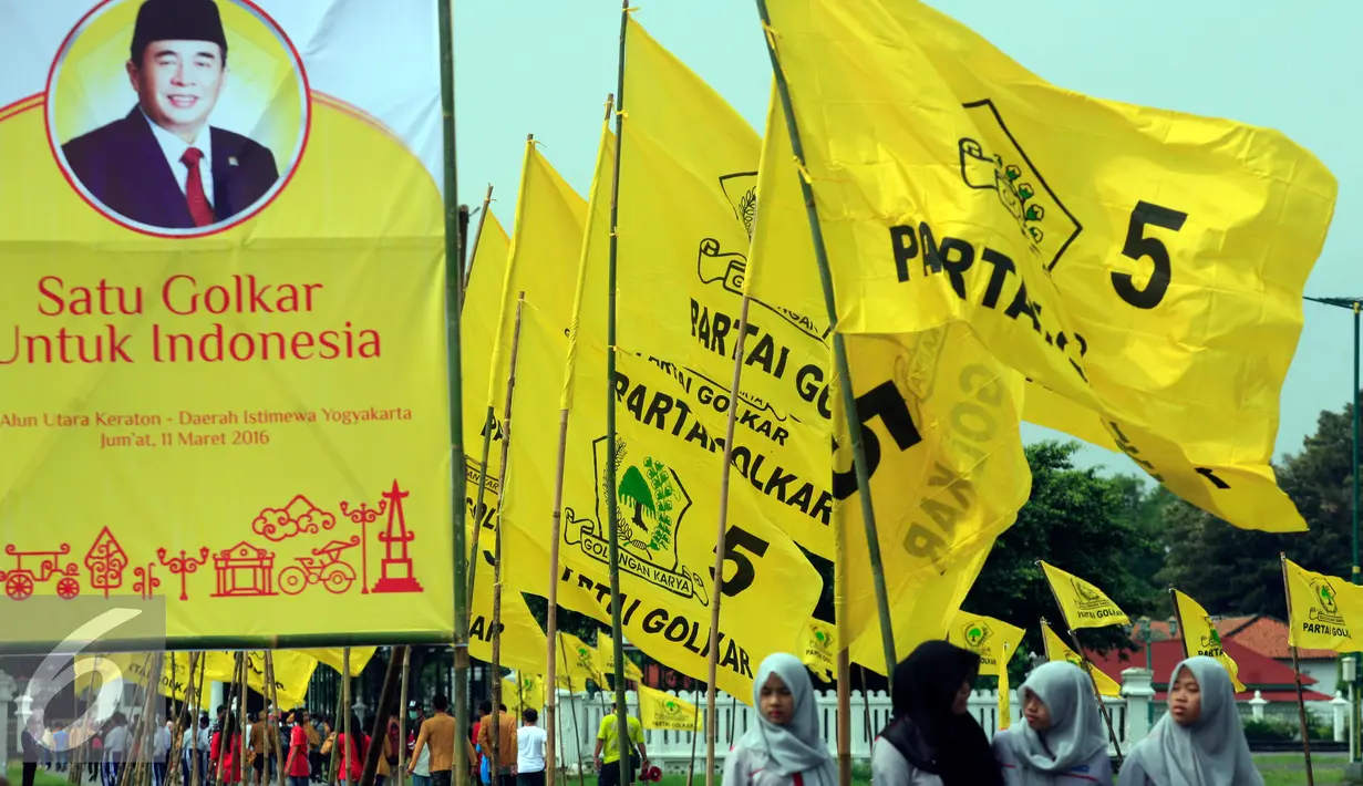 Wisatawan melintasi baliho Ade Komarudin dan bendera partai golkar di kawasan alun alun utara Yogyakarta (11/3/2016). Ade Komarudin akan mendekalrasikan pencalonan ketua Umum DPP Golkar yang akan bertarung pada Munaslub 2016. (Liputan6.com/Boy Harjanto)