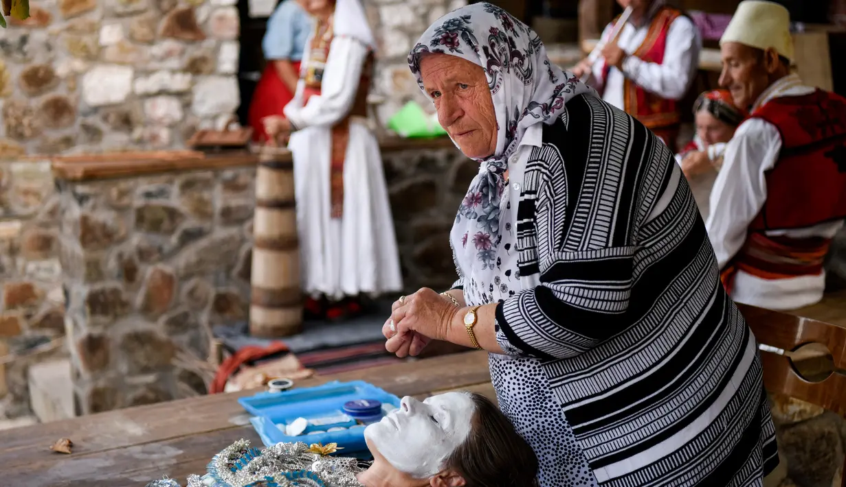 Wanita Kosovo, Sheqerie Buqaj saat menerima lukisan wajah tradisional di Desa Kukaj, Kosovo, Rabu (5/9). Tradisi melukis wajah untuk pengantin wanita ini sudah ada sejak berabad-abad silam. (ARMEND NIMANI/AFP)