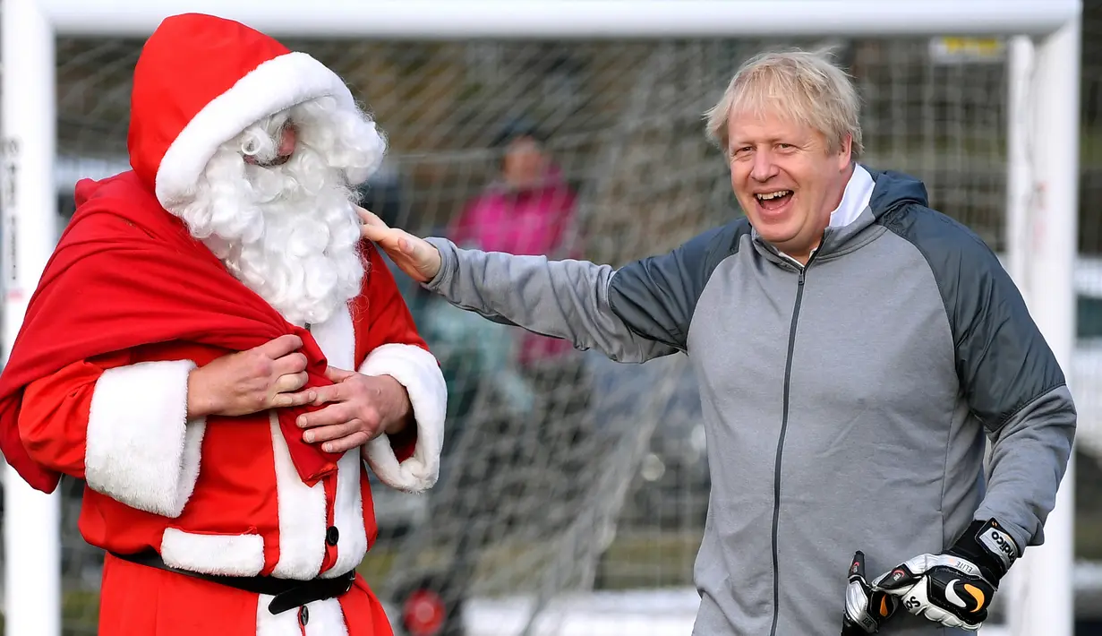 PM Inggris Boris Johnson menyapa pria berpakaian Sinterklas sebelum pertandingan sepak bola putri junior antara Hazel Grove United JFC dan Poynton di Cheadle Hulme, Inggris, Sabtu (7/12/2019). Aksi itu dalam rangka kampanye jelang pemilu Inggris 12 Desember 2019. (Toby Melville/Pool Photo via AP)