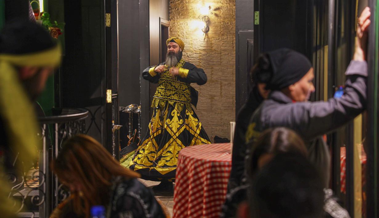 Usai berbuka puasa di bulan suci Ramadan, salah satu restoran di Damaskus, Suriah, menggelar pertunjukan yang lain dari biasanya, yakni tarian sufi. Tampak dalam foto, seorang penari bersiap di belakang panggung sebelum para darwis berputar menampilkan tarian Sufi di sebuah restoran selama pertunjukan yang diadakan setelah berbuka puasa selama bulan suci Ramadan 1447 Hijriah, di distrik bersejarah Damaskus, Suriah, Minggu 22 Februari 2026. (AP Photo/Ghaith Alsayed)