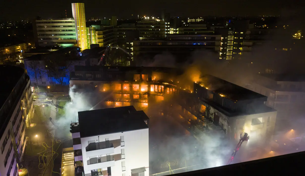 Petugas pemadam kebakaran memadamkan api di kompleks perumahan di Essen Jerman, Senin (21/2/2022). Dinas pemadam kebakaran mengatakan bahwa sekitar 100 orang dievakuasi dari kompleks apartemen tersebut. (Stephan Witte/KDF-TV/dpa via AP)