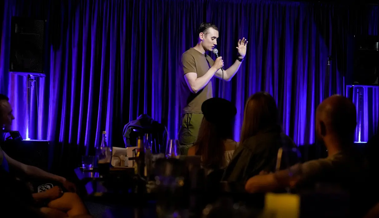 Komika Serhiy Lipko tampil pada pertunjukan stand-up comedy di Kyiv, Ukraina, 11 Juni 2022. Perang Ukraina tidak terlalu lucu, tetapi orang-orang di sana belajar menertawakan kengerian itu semua untuk tetap waras dalam konflik yang telah menewaskan puluhan ribu orang tersebut. (AP Photo/Natacha Pisarenko)