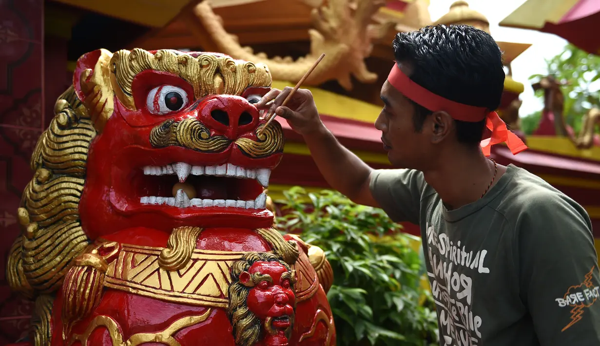 Seorang pekerja mengecat patung di depan kuil Cina di Denpasar, Bali, Senin (23/1). Pengecatan ini dilakukan dalam rangka menyambut pergantian tahun baru Imlek 2568. (AFP PHOTO / SONNY Tumbelaka)