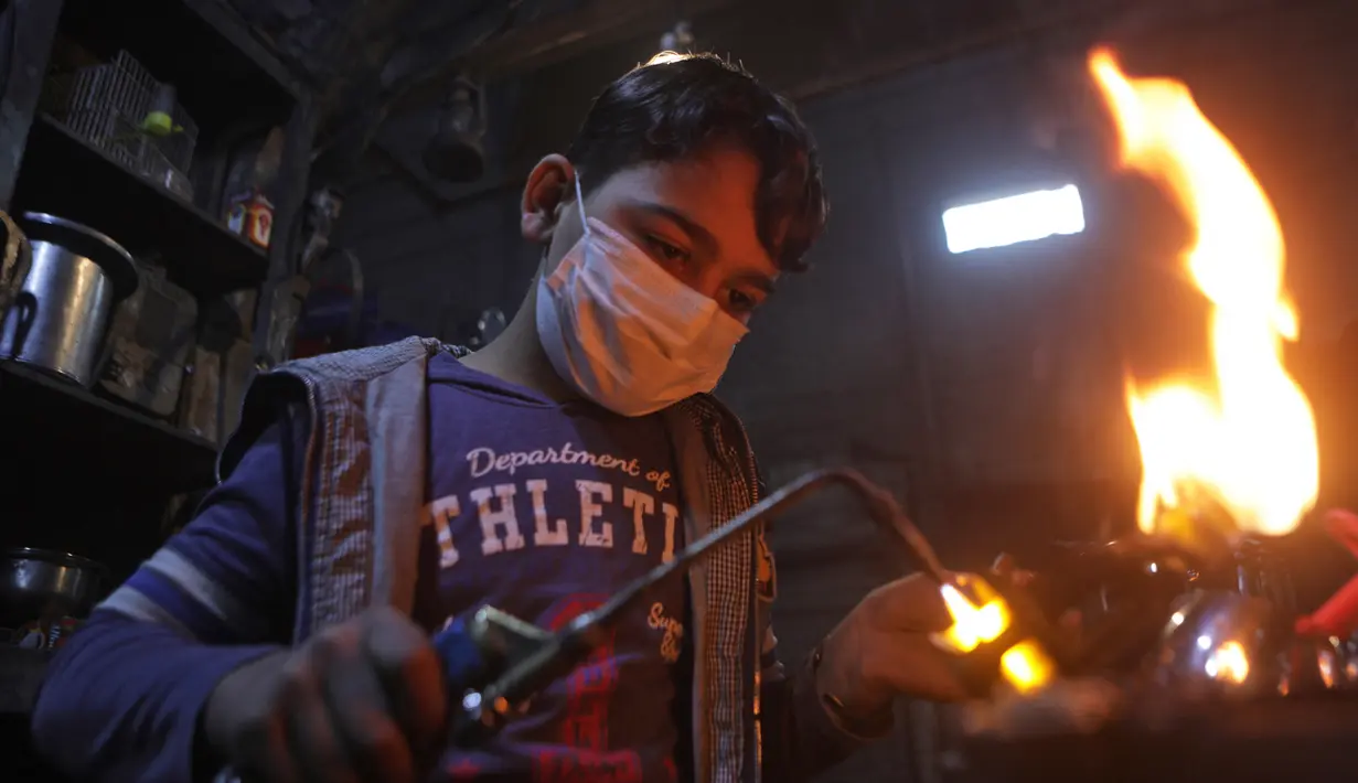 Nadim al-Nako (12) bekerja membuat panci dan wajan di bengkel ayahnya di utara Kota al-Bab yang dikuasai Turki, Suriah, 20 November 2021. Menurut UNICEF, setelah satu dekade perang diperkirakan 2,5 juta anak-anak Suriah putus sekolah. (Bakr ALKASEM/AFP)