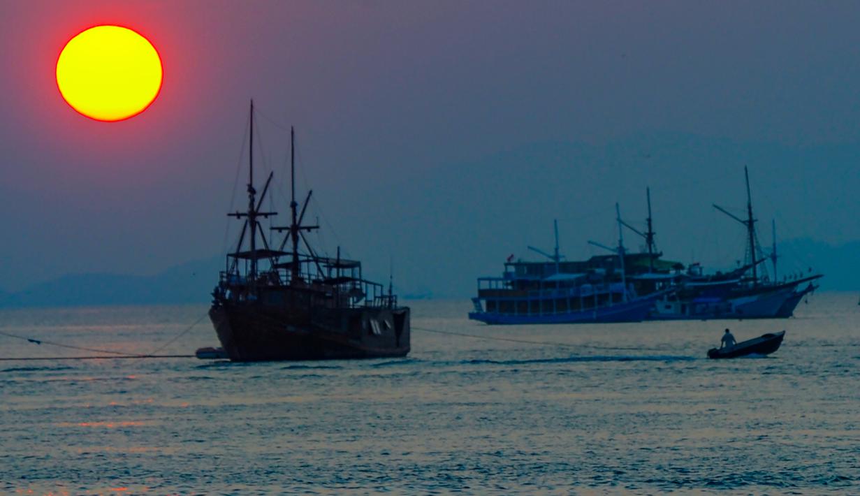 Keindahan Labuan Bajo tidak hanya terletak pada keberadaan satwa purba Komodo, tetapi juga pada pesona matahari terbenam yang tersaji hampir di setiap sudut kota. Tampak dalam foto, Sebuah perahu melintas di perairan Labuan Bajo, Flores, Nusa Tenggara Timur sesaat sebelum matahari terbenam. (merdeka.com/Arie Basuki)