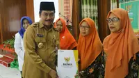 Wakil Bupati Gresik Dr. Mohammad Qosim didampingi Ketua Baznas Kabupaten Gresik H. Abd. Munif, secara simbolis membagikan dana insentif kepada guru dan penghafal Al-Quran. (Foto: Liputan6.com/Dian Kurniawan)