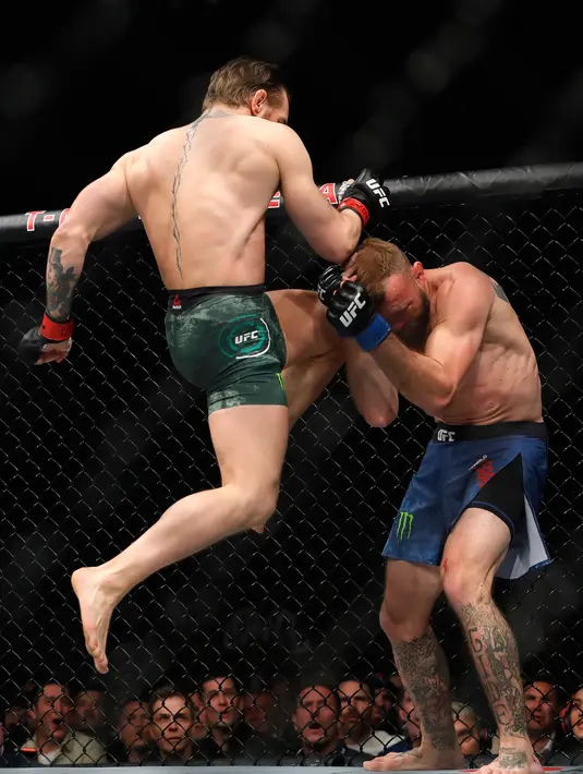 Conor McGregor (kiri) menghantamkan lututnya ke wajah Donald 'Cowboy' Cerrone pada pertarungan kelas welter UFC 246 di T-Mobile Arena, Las Vegas, Amerika Sertikat, Sabtu (18/1/2020). McGregor mengalahkan Cowboy pada detik ke-40. (Steve Marcus/Getty Images/AFP)
