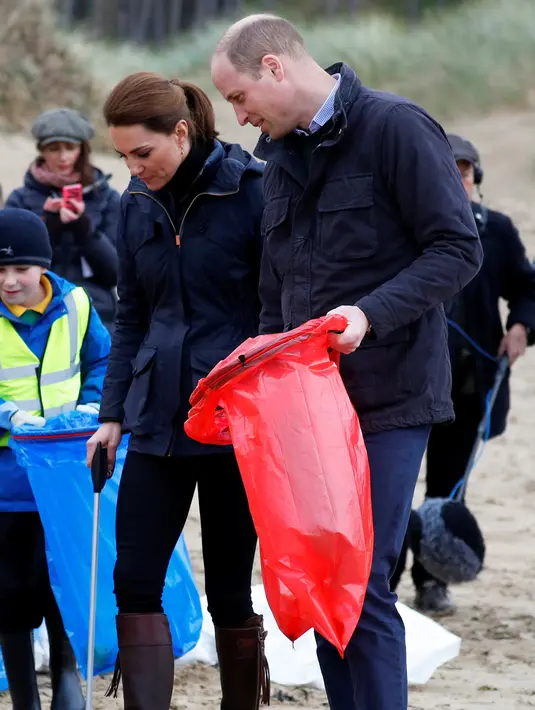 Pangeran William dan Kate Middleton, Duchess of Cambridge saat membantu anak-anak sekolah membersihkan sampah di pantai Newborough di Wales (8/5). Pangeran William dan Kate Middleton melakukan kunjungan ke pantai Newborough untuk membersihkan sampah yang berserakan. (Reuters/Phil Noble)