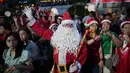 Seorang peserta yang mengenakan kostum Santa Claus menjadi pusat perhatian warga di sela-sela bernyanyi bersama. Tampak dalam foto, seorang pria berpakaian Santa Claus menyanyikan lagu-lagu Natal di Jakarta, Indonesia, Selasa, 23 Desember 2025. (AP Photo/Dita Alangkara)