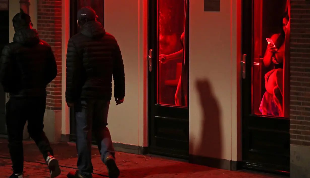 Orang-orang berjalan melewati rumah bordil di Red Light District Amsterdam, Belanda, Rabu (3/4). Pemerintah Amsterdam melarang tur prostitusi di kawasan tersebut karena banyak keluhan dari pekerja seks komersial (PSK). (REUTERS/Yves Herman)