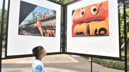 Siswa SD Negeri Menteng 01 mengamati karya foto yang dipamerkan dalam pameran fotografi Rekam Jakarta di Taman Menteng, Kamis (29/8/2019). Kegiatan tersebut dalam rangka edukasi bagi siswa mengenal profesi foto jurnalistik. (merdeka.com/Iqbal S Nugroho)