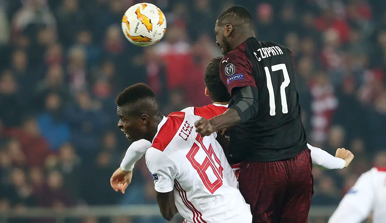 Pemain AC Milan Cristian Zapata melompat untuk merebut bola dari pemain Olympiakos Piraeus, Pape Abou Cisse dalam laga keenam Grup F Liga Europa di Stadion Georgios Karaiskakis, Kamis (13/12). AC Milan takluk 1-3 dari Olympiacos. (AP/Petros Giannakouris)