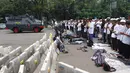 Massa aksi damai 4 November melaksanakan salat Jumat di Jalan Merdeka Barat, Jakarta, Jumat (4/11). Mereka menggelar salat Jumat di belakang pembatas beton dan mobil barakuda yang mengamankan kawasan itu. (Liputan6.com/Faizal Fanani)